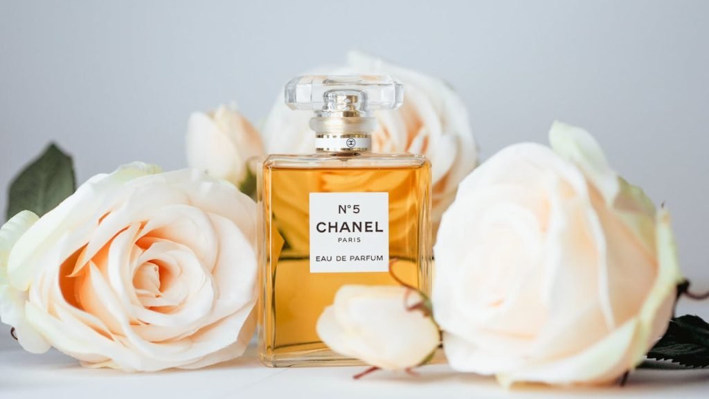 Chanel No 5 perfume bottle surrounded by elegant white roses, symbolizing luxury and femininity.